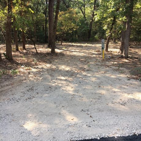 An image showcasing RV sites nestled among lush, manicured oak trees, highlighting the serene and shaded environment for a relaxing stay at Lavender Place & RV.